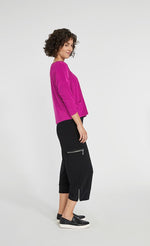 Load image into Gallery viewer, Right side full body view of a woman wearing black pants and the Sympli Spark Boxy Top. This top is flamingo colored. It has two front patch pockets, a scoop neck, and 3/4 length sleeves.
