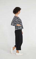Load image into Gallery viewer, Right side full body view of a woman wearing black pants and the Sympli Spark Boxy Top. This top has black and white shifted stripes. It has two front patch pockets, a scoop neck, and 3/4 length sleeves.
