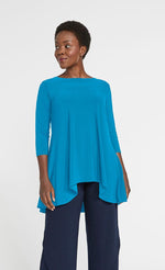Load image into Gallery viewer, Front top half view of a woman wearing the sympli true t in the color splash. This color is a sky blue. The top has 3/4 length sleeves, a boat neck, and a flowy high-low hem with longer sides.
