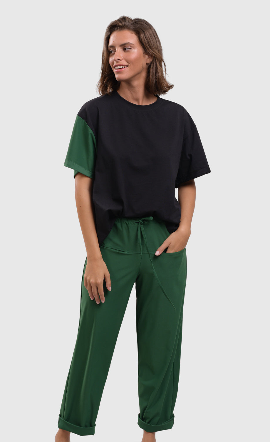 Front full body view of the alembika tekbika green drawstring pants. These pants are rolled up at the bottom and have two front pockets. The pant also has a drawstring waistband and a straight silhouette.