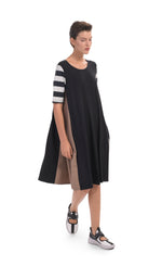 Load image into Gallery viewer, Front, full body view of a woman wearing the alembika tekbika stripe dress. This dress is black with one brown side, one striped side, and striped elbow length sleeves. The dress sits at the knees.
