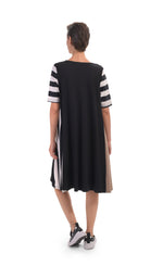 Load image into Gallery viewer, Back, full body view of a woman wearing the alembika tekbika stripe dress. This dress is black with one brown side, one striped side, and striped elbow length sleeves. The dress sits at the knees.
