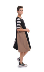 Load image into Gallery viewer, Right side, full body view of a woman wearing the alembika tekbika swing dress. This dress is black with one brown side and striped elbow length sleeves. The dress sits at the knees.
