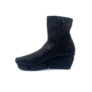 Inner side view of the trippen flaw boot in black waw. The inner side has a zipper. The boot has a black wedged sole.