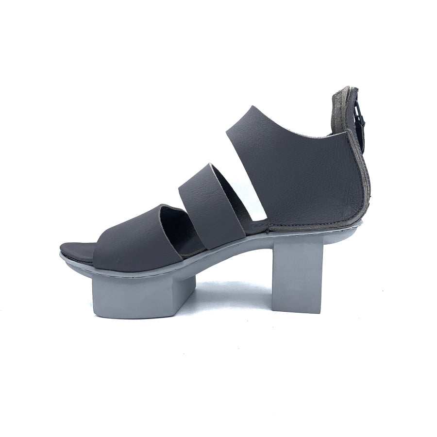 Inner view of trippen glitter sandal. This sandal is grey with a white/grey sole. The Sandal has wide straps that stripe the foot and a closed heel. The sole is a platform with two large, separated cubes.