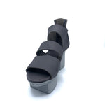 Load image into Gallery viewer, Front inner view of trippen glitter sandal. This sandal is grey with a white/grey sole. The Sandal has wide straps that stripe the foot and a closed heel. The sole is a platform with two large, separated cubes.
