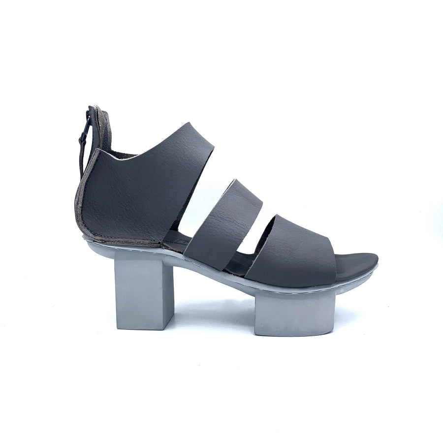 Outer view of trippen glitter sandal. This sandal is grey with a white/grey sole. The Sandal has wide straps that stripe the foot and a closed heel. The sole is a platform with two large, separated cubes.