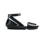 Load image into Gallery viewer, Outer view of the trippen iris sandal in black. This flat sandal has a wide strap over the toes, leather that covers the heel, and an ankle strap that criss crosses and attaches to the sole on both sides of the shoe.
