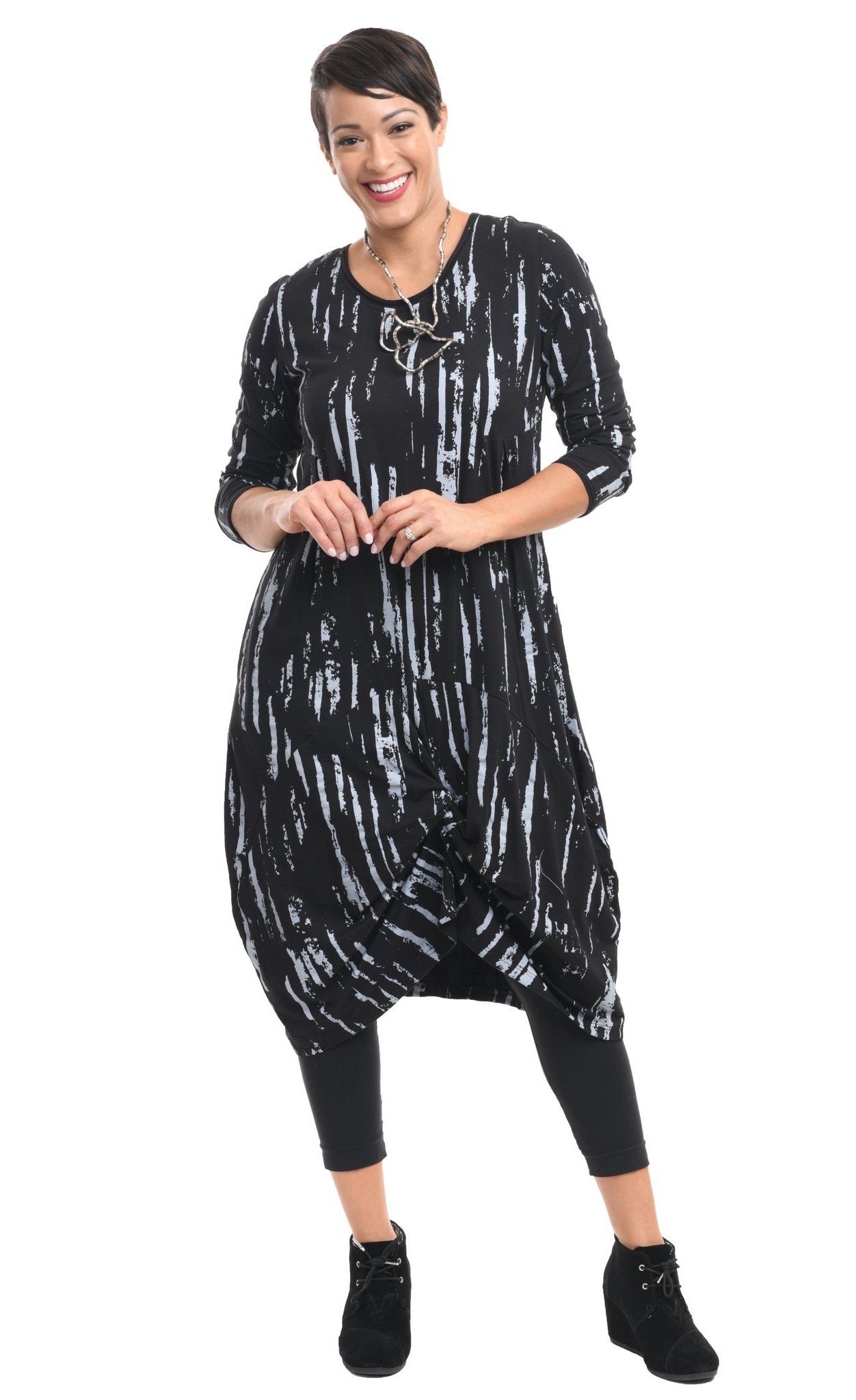 Front full body view of a woman wearing the tulip karma dress in black with a grey airbrush print. The dress has long sleeves and a gathered knot in the front.
