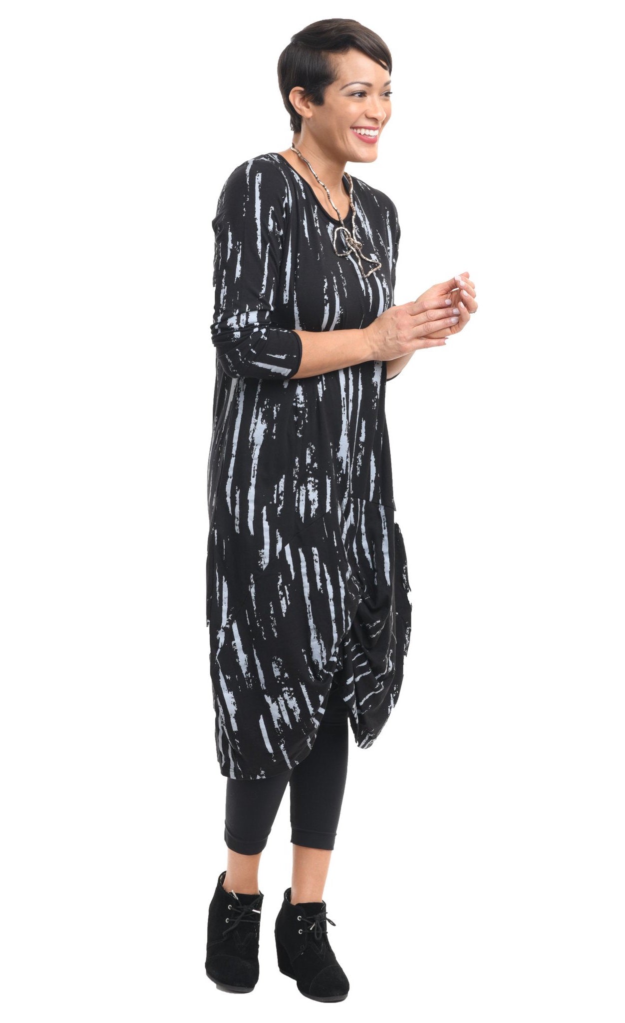 Front full body view of a woman wearing the tulip karma dress in black with a grey airbrush print. The dress has long sleeves and a gathered knot in the front.
