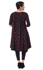 Load image into Gallery viewer, Back full body view of a woman wearing the tulip lexi tunic dress in black with cherry cracker print all over it. This dress has long sleeves and inverted pleats on the back
