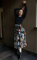Load image into Gallery viewer, Front full body view of a woman wearing the long unbreakable evolution gio skirt in the black and white print with hints of colors. This print features different images of stars from the 50s and 60s.

