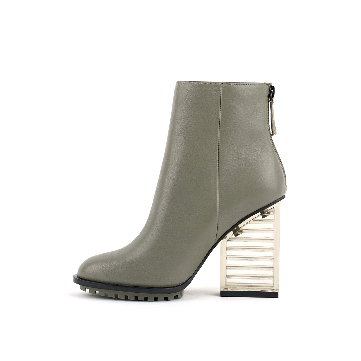Inner side view of the united nude hi rise bootie. This bootie is grey with a glass like see-through, block shaped high heel. The bootie is an ankle bootie with a back zipper.