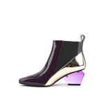 Load image into Gallery viewer, Inner side view of the united nude jacky h bootie. This bootie sits at the ankles. The top of the shoe is midnight brown. The bottom part of the shoe is silver. This bootie has elastic sides and a purple glass like heel.
