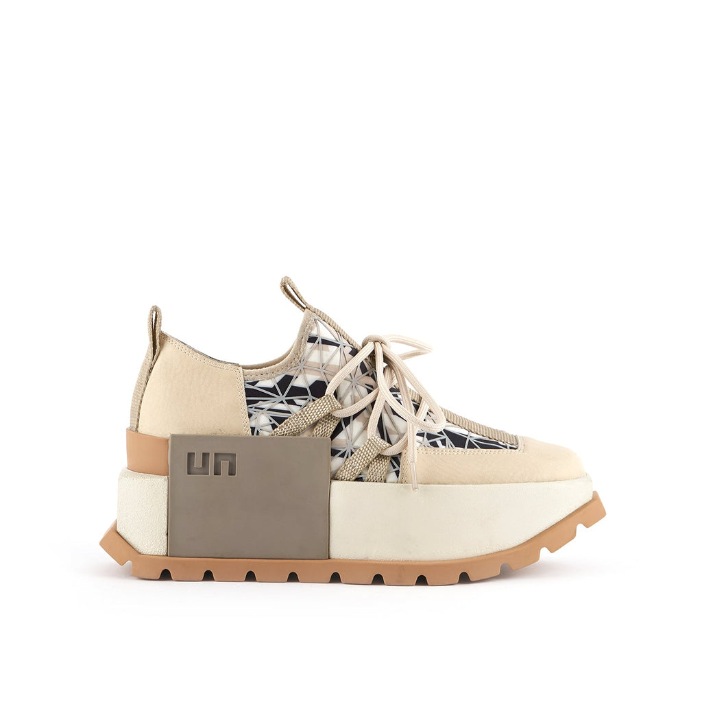 outer side view of the united nude roko hype sneaker in the color beige/natural. This sneaker has a wedge platform sole, a lace up front, a black and white geometric design, and a decorative square on the outer side with the United Nude logo.