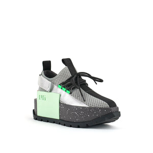 Front outer side view of the united nude roko space sneaker. This sneaker sis grey with a platform sole. The upper is a mesh-like fabric. The shoes has a back strap and a lace up front.