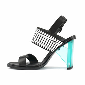 Inner view of the united nude spark sandal hi II. This high heel has a strap over the instep and a strap over the toes. This shoe is black with a blue heel and it has an adjustable buckle strap behind the heel.