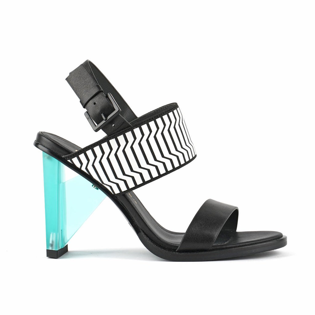 Outer view of the united nude spark sandal hi II. This high heel has a strap over the instep and a strap over the toes. This shoe is black with a blue heel and it has an adjustable buckle strap behind the heel.