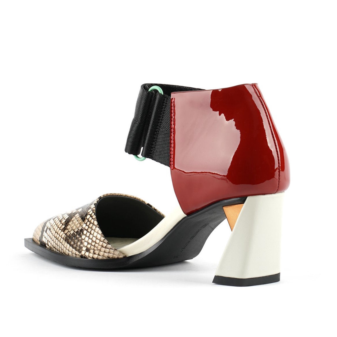 Inner back view of the united nude vita dorsey mid viper. This sandal has a pointed toe in snake skin and a red patent leather covered with a wide nylon adjustable strap around the front of the ankle. This sandal has a mid-heel with a gold and silver accent.