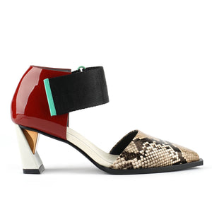Outer view of the united nude vita dorsey mid viper. This sandal has a pointed toe in snake skin and a red patent leather covered with a wide nylon adjustable strap around the front of the ankle. This sandal has a mid-heel with a gold and silver accent.