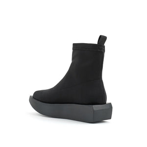 Inner back side view of the united nude wa bootie lo. This bootie is black and minimal. It has a sock-like appearance with a black platform sole.