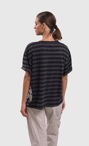 Back top half view of a woman wearing the alembika urban stripe moon boxy tee. This top has grey and black striping, a crew neck, a wide silhouette, and short sleeves.