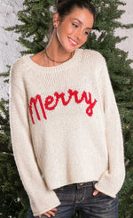 Load image into Gallery viewer, Front top half view of a woman wearing jeans and the wooden ship merry chunky crew sweater in the color alabaster/ginger. This sweater is white with the word merry written in red cursive on the front.
