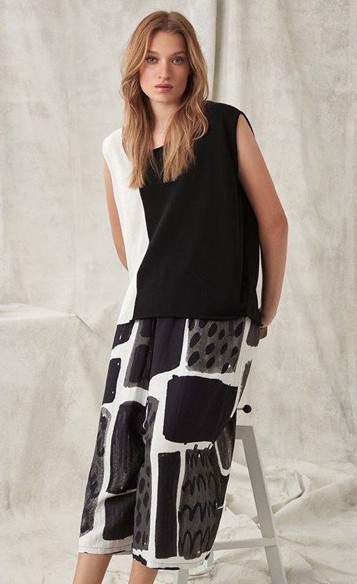 Front full body view of a woman wearing a black and white top with the crea concept black and white print pant. This pant has an abstract print on it, and a wide leg.