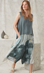 Load image into Gallery viewer, Front full body view of a woman wearing a faded teal tank and the crea concept abstract watercolor pant. This pant is wide legged and has a teal watercolor-like print on it. 
