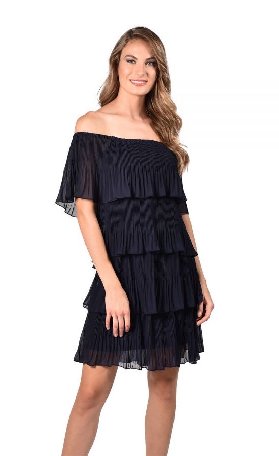 Front full body view of a woman wearing the frank lyman tiered dress in midnight blue. This dress is off the shoulder with tiered fabric that creates a waterfall effect. The dress ends right above the knees.