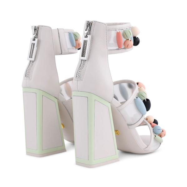 Back, outer view of a pair of the kat maconie cardi high-heel. This shoe is white with three straps. Each strap is decorated with pastel colored beads. The heel is geometric with pastel green outlining. The back of the shoe features a zipper.