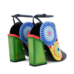 Back outer side view of a pair of the kat maconie frida glitch high heel. This shoe features bright mutlicolored circles on the upper with a black strap over the toes and a black ankle strap. The high heel is green.
