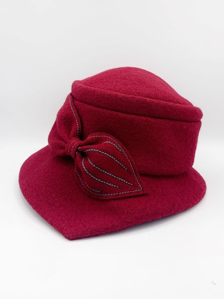 left side view of the lillie & Cohoe grace red/ruby hat. This hat has a pointed brim and a bow  in the front.