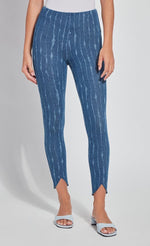 Load image into Gallery viewer, Front bottom half view of a woman wearing the lysse lynette scallop edge denim pattern legging. The leggings are a mid-wash denim color with white streaks running vertically down the leg. The pants are high-waisted and have a tulip shaped cut at the hem near the ankles. 
