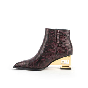 inner side view of the united nude un bootie mid in the color dark cherry. This bootie has a pointed toe, and snakeskin print on the upper, and a gold colored metal heel.