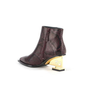 inner back side view of the united nude un bootie mid in the color dark cherry. This bootie has a pointed toe, and snakeskin print on the upper, and a gold colored metal heel.