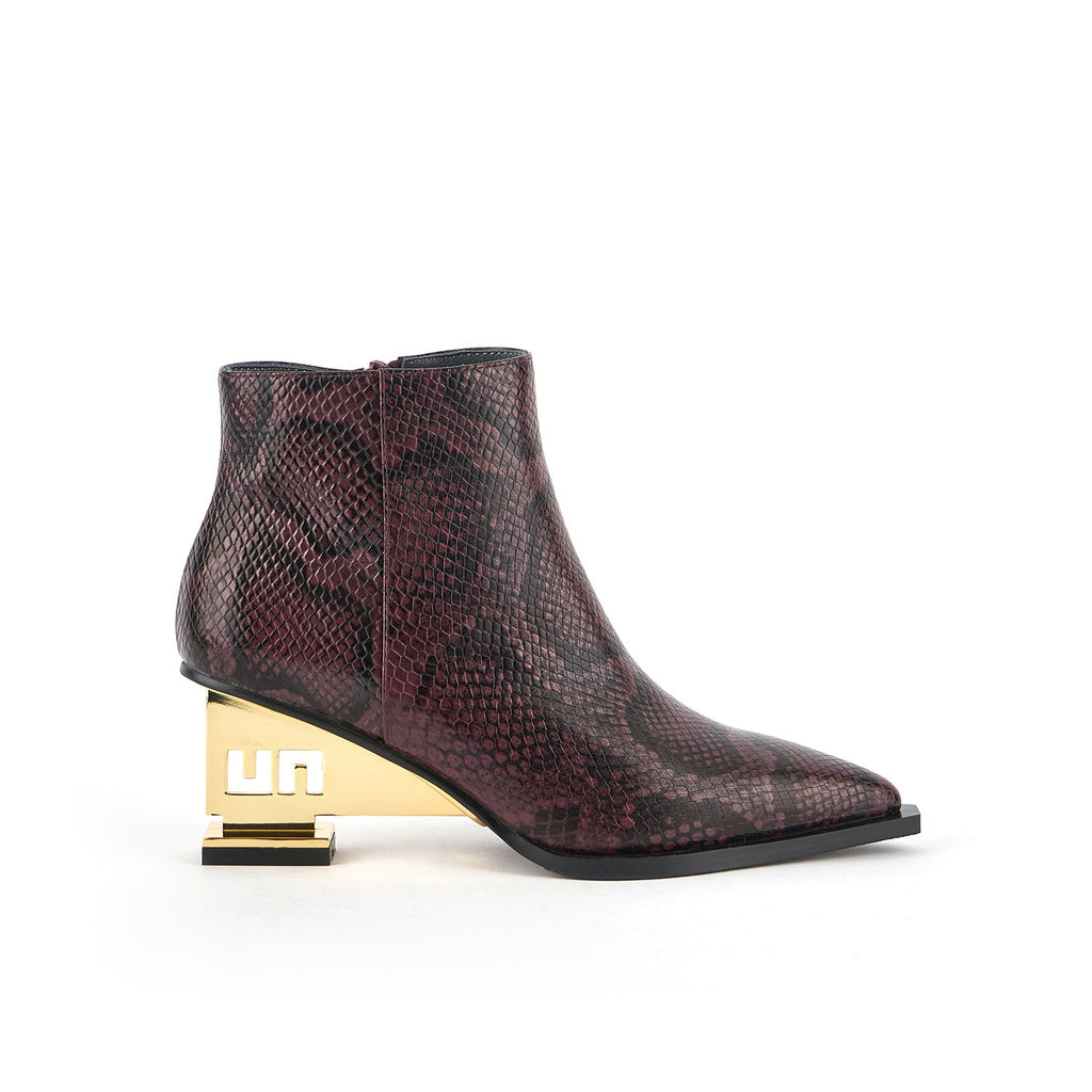 outer side view of the united nude un bootie mid in the color dark cherry. This bootie has a pointed toe, and snakeskin print on the upper, and a gold colored metal heel.