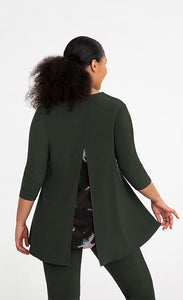 Back top half view of a woman wearing the sympli nu whisper split back top. This top is in the color green/seaweed with a mineral print peeking out from behind a slit in the back. The top has 3/4 length sleeves and a round neck.